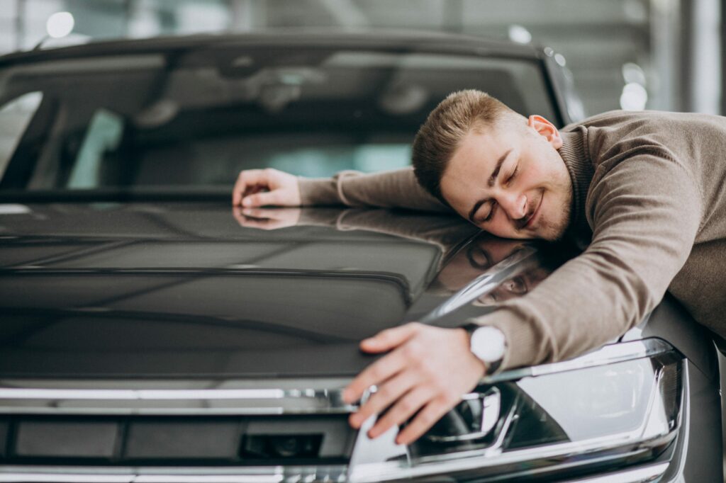 young handsome man hugging car car showroom scaled 1